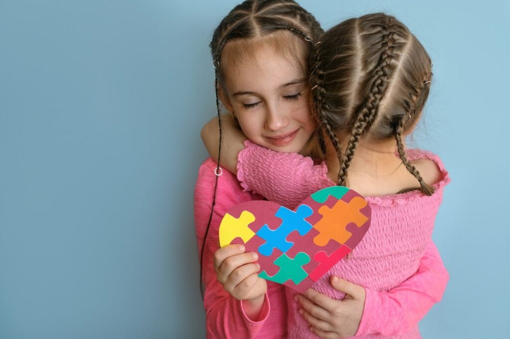 Girl hugs autistic sister tightly as sign of support and comforts.